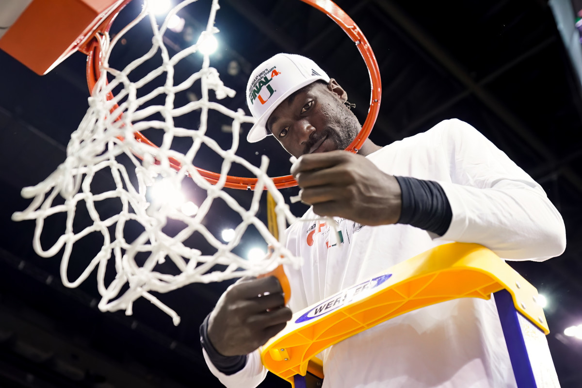 Miami center Favour Aire cuts down the net after the Hurricanes defeated Texas in the 2022 NCAA Men's Basketball Tournament.