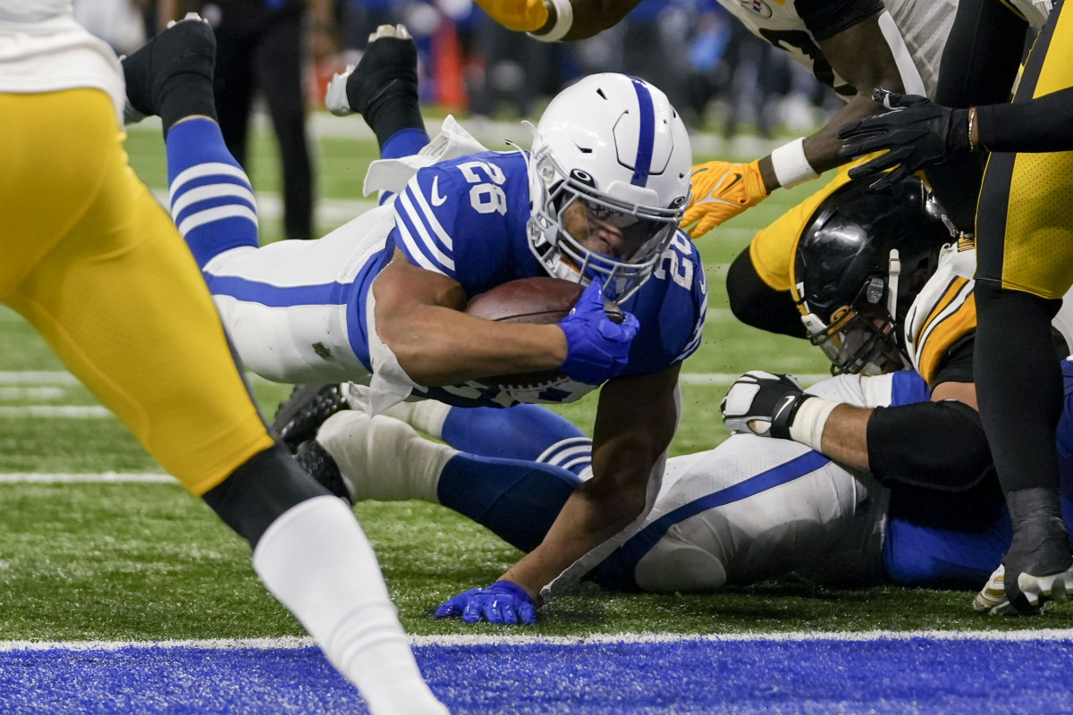 Indianapolis Colts running back Jonathan Taylor dives into the end zone with the ball in one hand as Steelers players swarm him