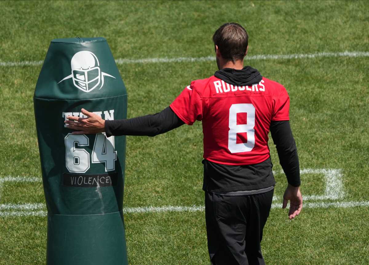 QB Aaron Rodgers walks by a tackling dummy at Jets' OTAs