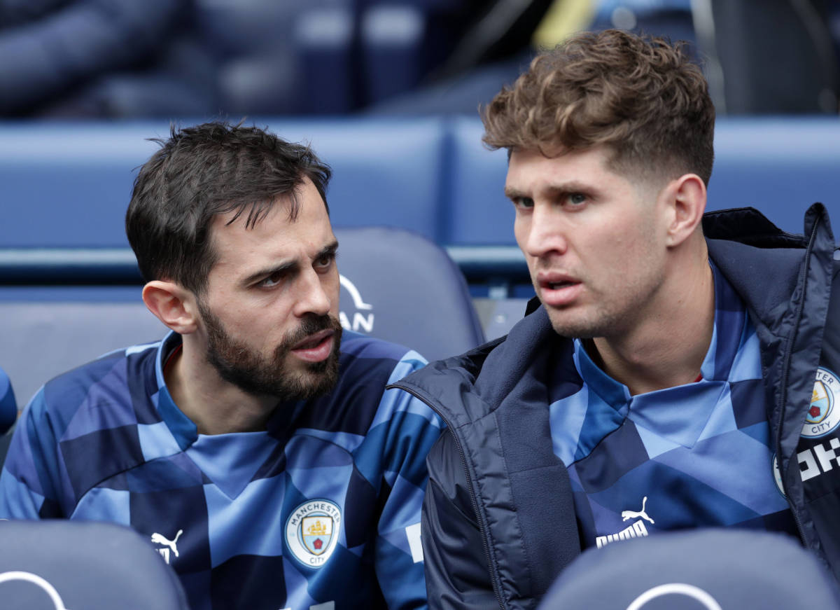 Manchester City teammates Bernardo Silva (left) and John Stones pictured together on the bench during a game in May 2023