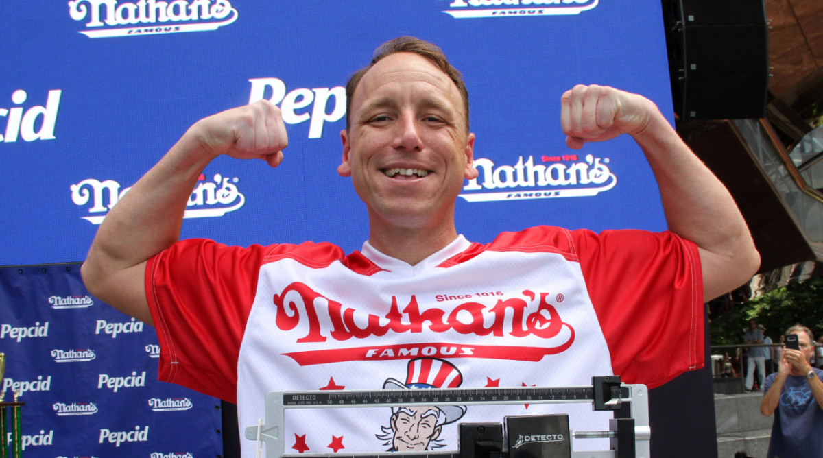 Hot dog eating contest competitor Joey Chestnut flexes during his weighing.