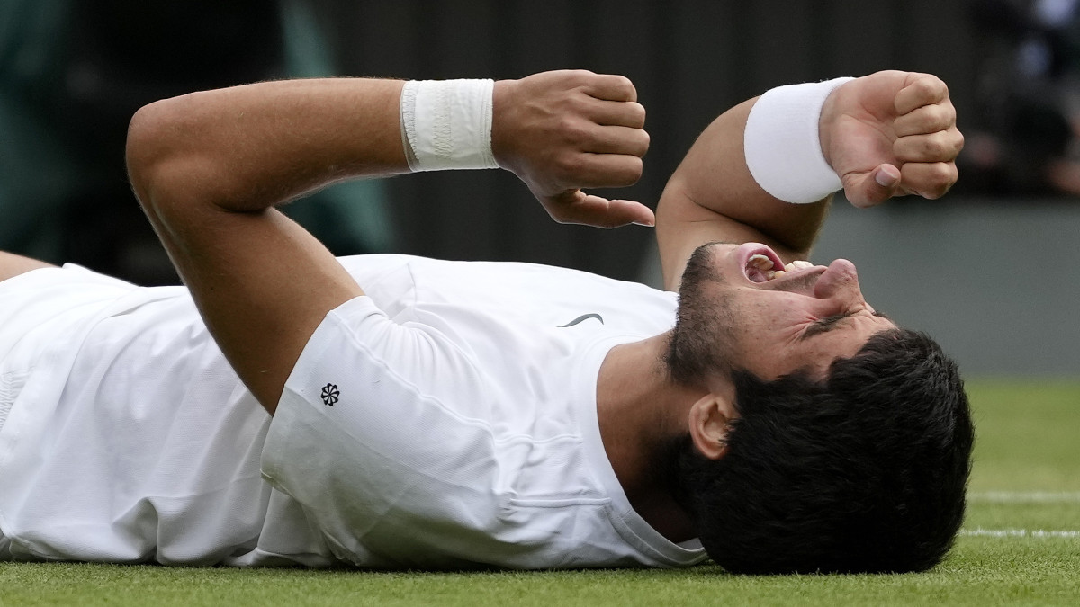 Carlos Alcaraz lies on the ground after winning Wimbledon