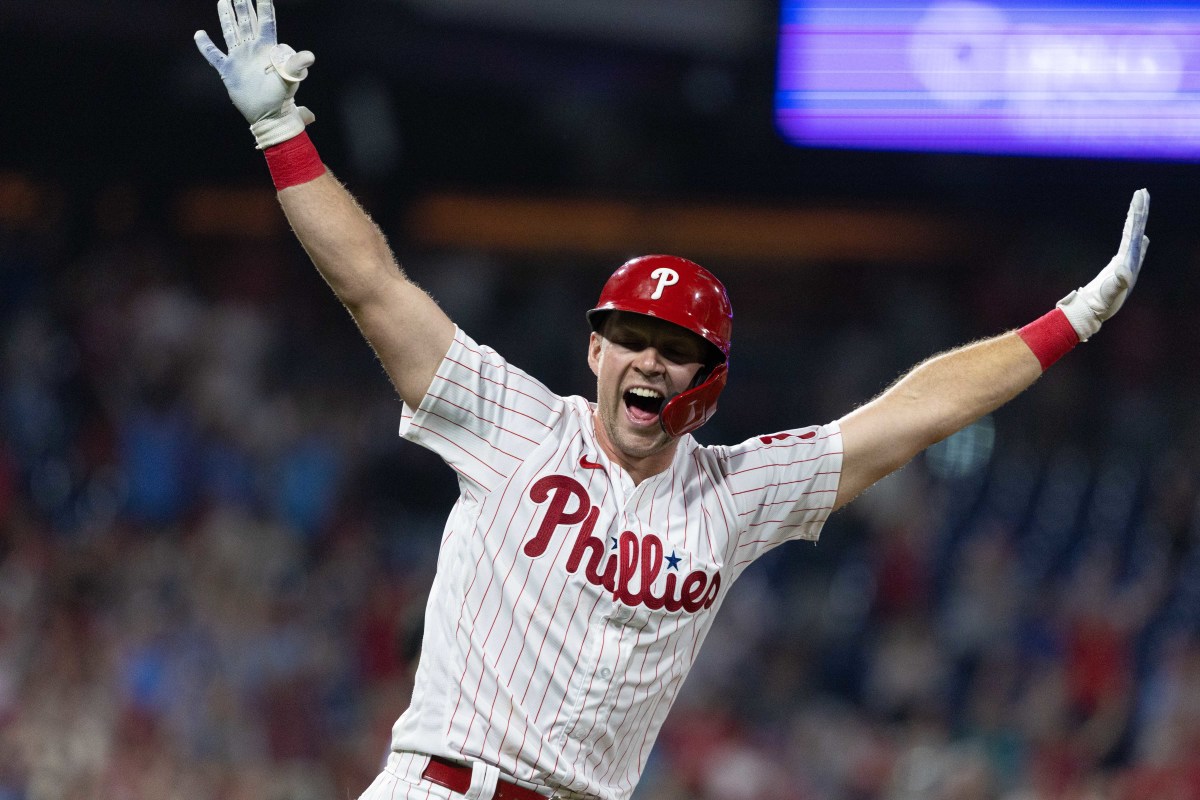 Philadelphia Phillies - Rhys Hoskins, wearing the cream Phillies uniform,  celebrating with the dugout after scoring a run.