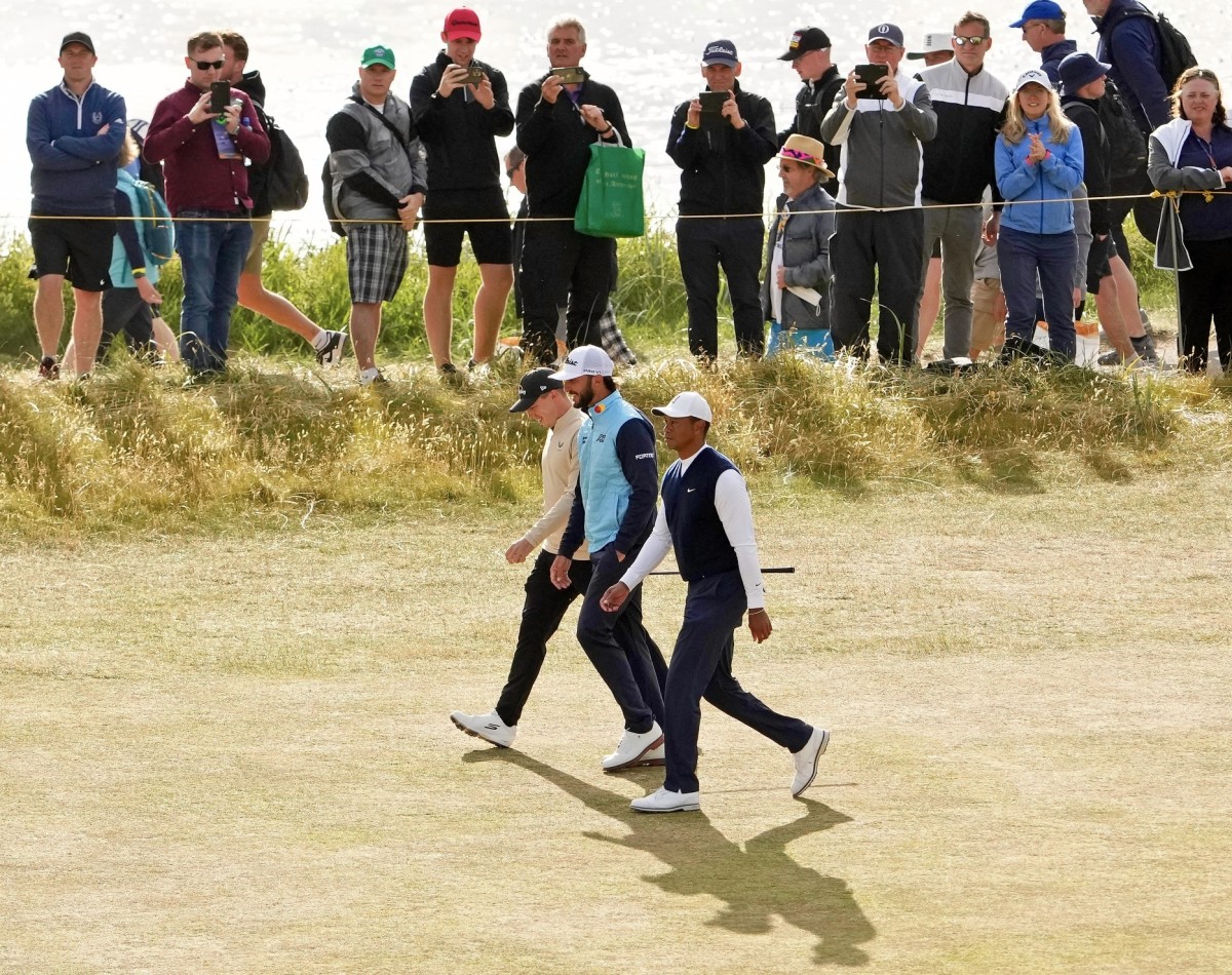 Max Homa, center, and Tiger Woods walk the fairway