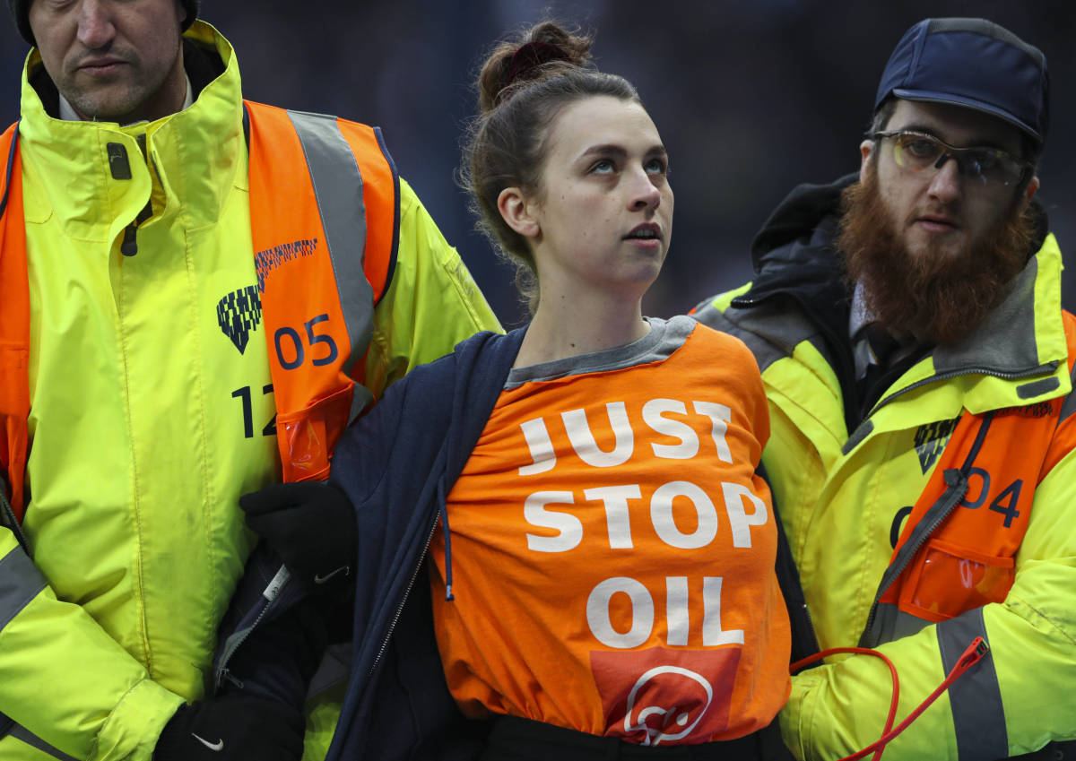 A woman is escorted away by security staff after attempting to stage a "Just Stop Oil' protest at Tottenham Hotspur Stadium