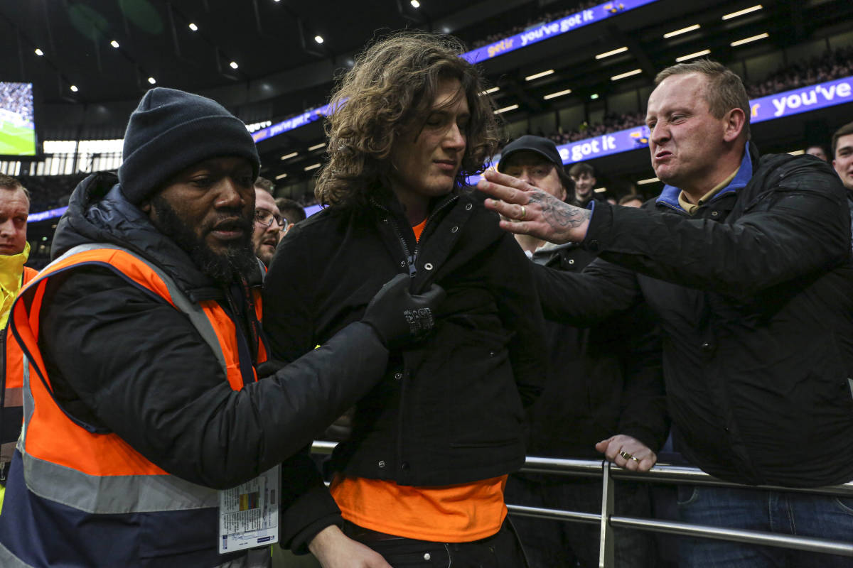 A man is taken away by a security steward after invading the pitch during Tottenham vs West Ham