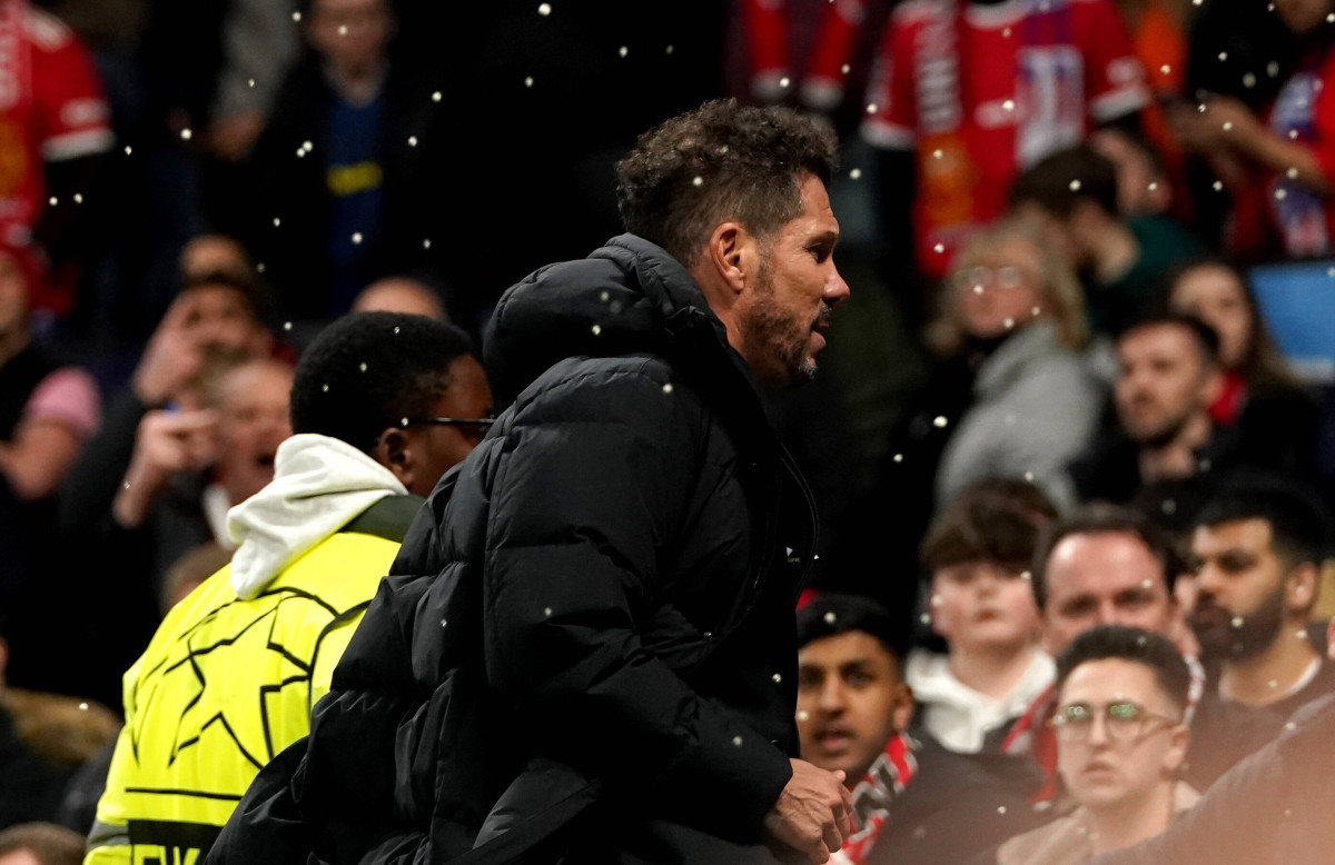 Liquid rains down near Diego Simeone after multiple Manchester United fans throw bottles and cups at the Atletico Madrid manager