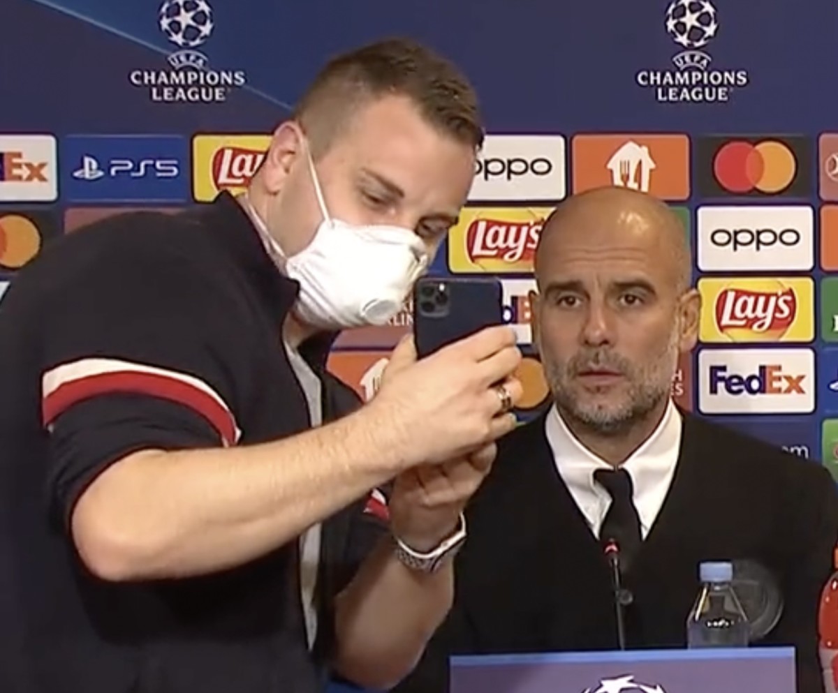 Manchester City manager Pep Guardiola pictured (right) awkwardly posing for a selfie with a journalist at a UEFA Champions League press conference in October 2022