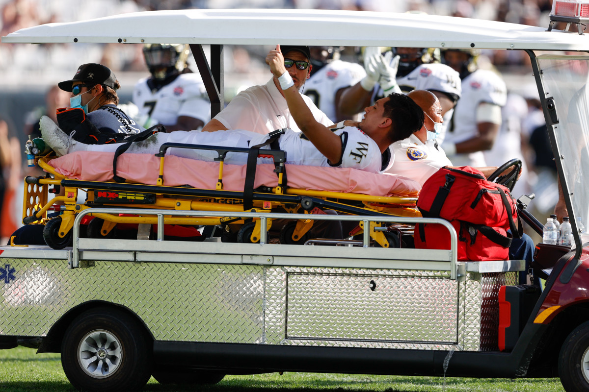 Mora gives a thumbs up to his teammates as he is carted off the field in the 2021 Gator Bowl