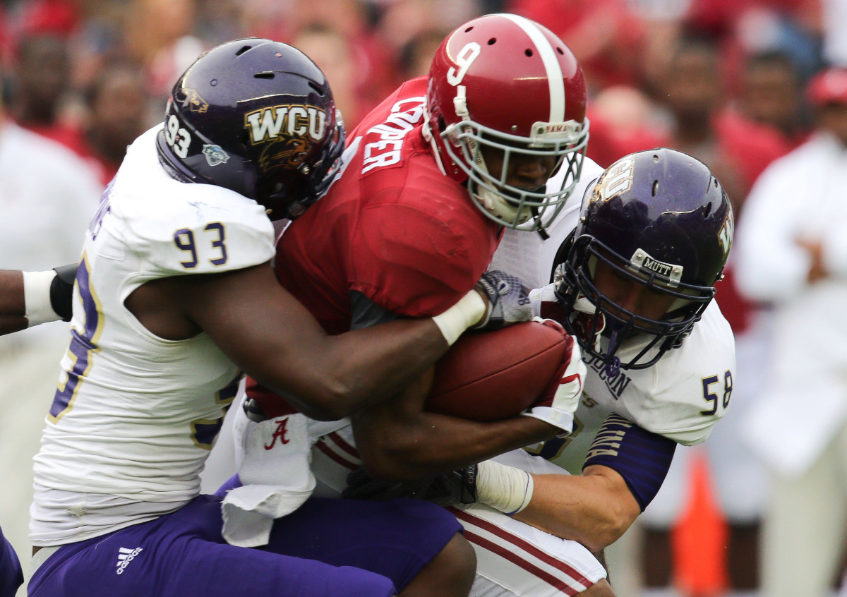 Alabama Crimson Tide wide receiver Amari Cooper (9) is tackled by Western Carolina Catamounts defensive end Caleb Hawkins (93) and linebacker Daniel Riddle (58) at Bryant-Denny Stadium.