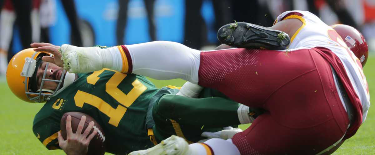 Green Bay Packers quarterback Aaron Rodgers (12) runs with the ball as he  is chased by Washington Commanders defensive tackle Daron Payne (94) on the  last play of an NFL football game