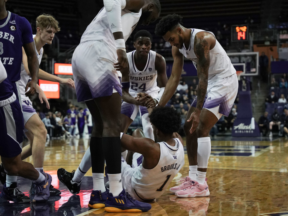 UW players scurry to help Keion Brooks Jr. off the floor.