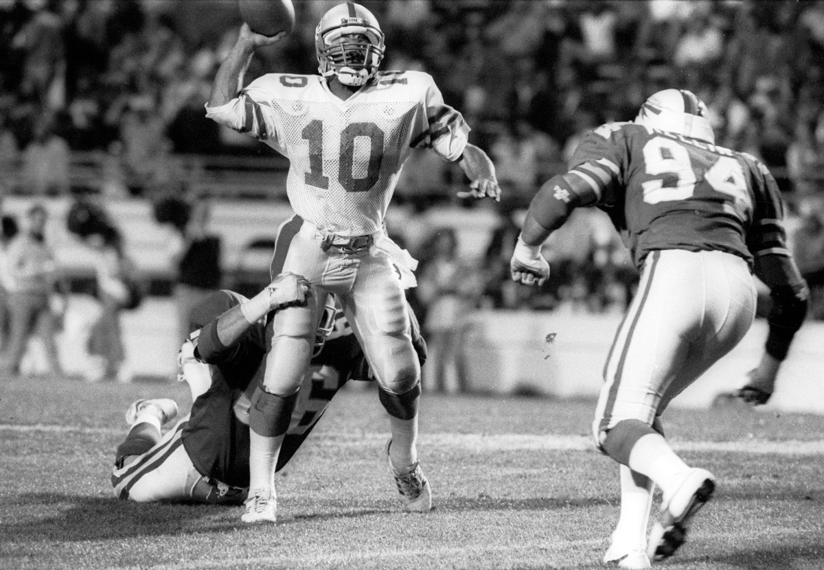 Orlando Renegades defensive tackle Scott Hutchinson (66) holds on to Memphis Showboats quarterback Walter Lewis (10) at the Citrus Bowl during the 1985 USFL season.