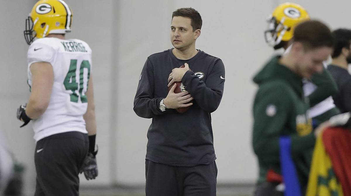 Packers executive Eliot Wolf holds a football while on the field during practice.