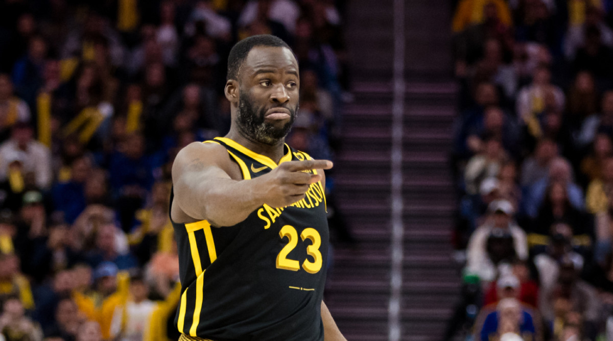 Draymond Green points while dribbling the ball during a Golden State Warriors game.