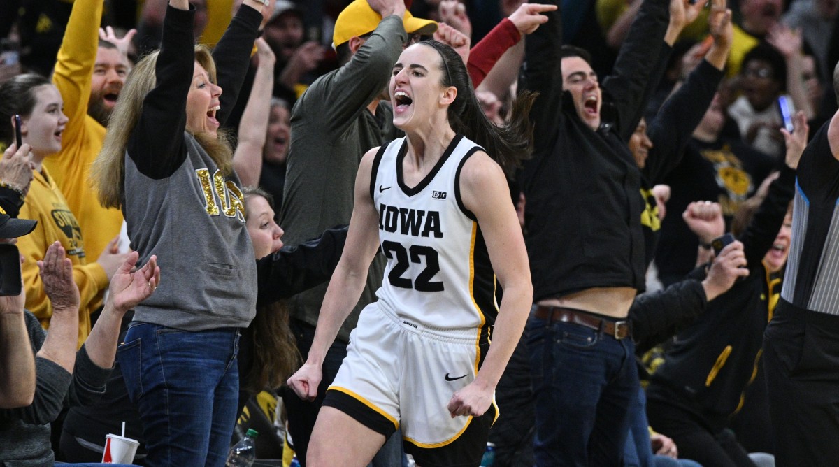 Iowa Hawkeyes guard Caitlin Clark (22) celebrates with fans after breaking the NCAA women's all-time scoring record during the first quarter of a game against the Michigan Wolverines.