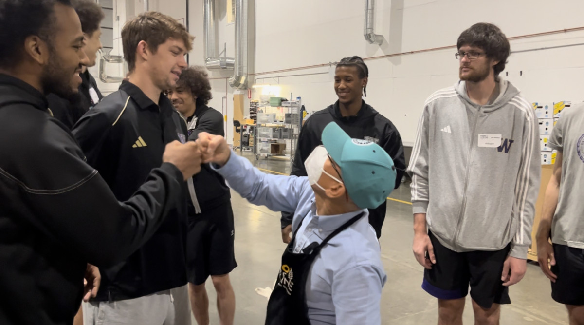 Washington men's basketball players Anthony Holland (far left), Paul Mulcahy (center left), Wesley Yates III (center right) and Wilhelm Breidenbach (far right) volunteering at Food Lifeline on Monday.