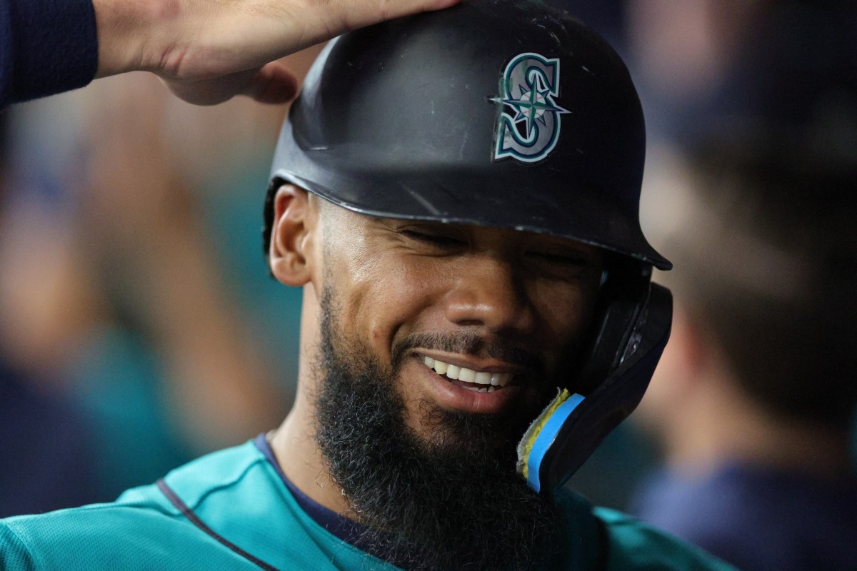 Seattle Mariners' Teoscar Hernandez holds a trident in the dugout as  teammates throw seeds at him to celebrate his solo home run against the  Kansas City Royals during the second inning of