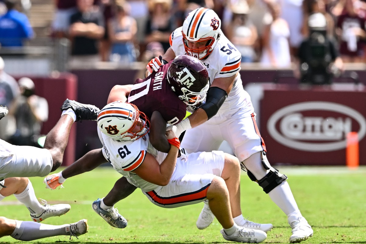 Sep 23, 2023; College Station, Texas, USA; Auburn Tigers long snapper Reed Hughes (61) and offensive lineman Tate Johnson (54) tackle Texas A&M Aggies wide receiver Ainias Smith (0) on a punt return in the third quarter at Kyle Field. Mandatory Credit: Maria Lysaker-USA TODAY Sports  