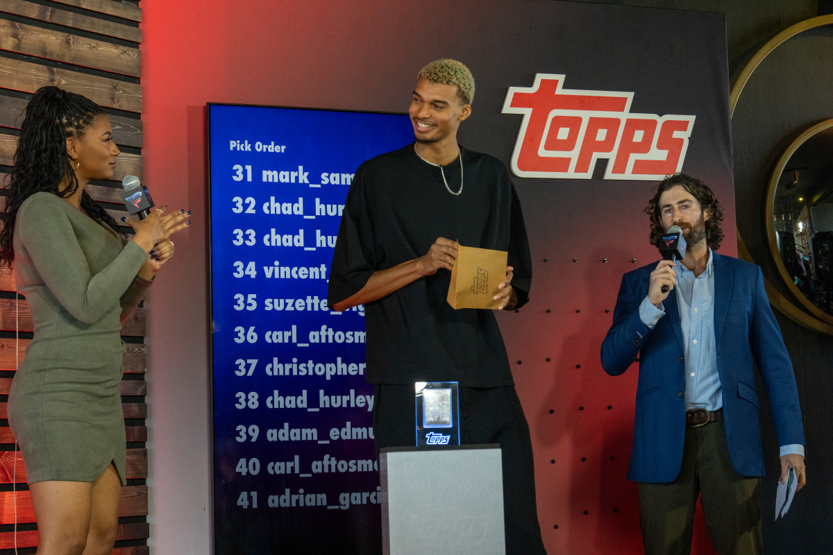 San Antonio Spurs rookie Victor Wembanyama smiles before reaching into a "Topps" envelope to reveal the winning number for his first-ever signed card.