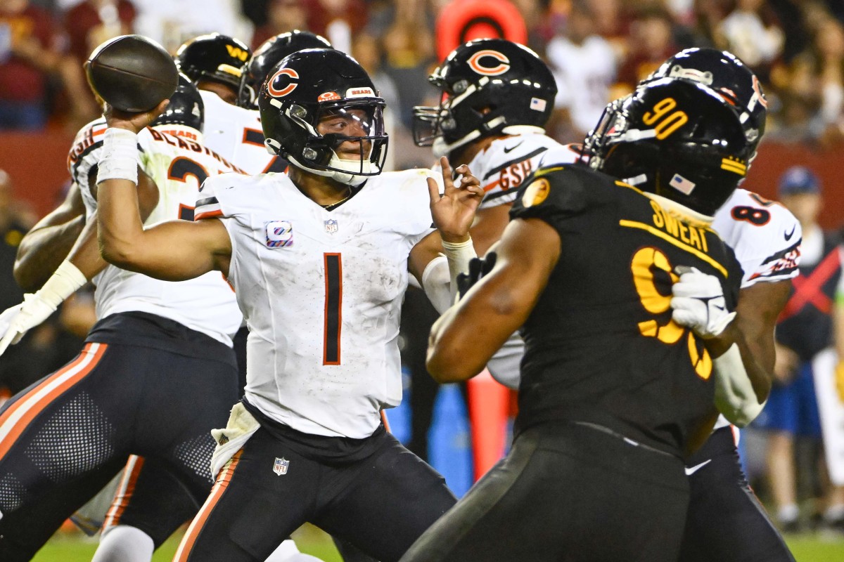 Justin Fields pulls his arm back to throw the ball as Montez Sweat rushes toward him