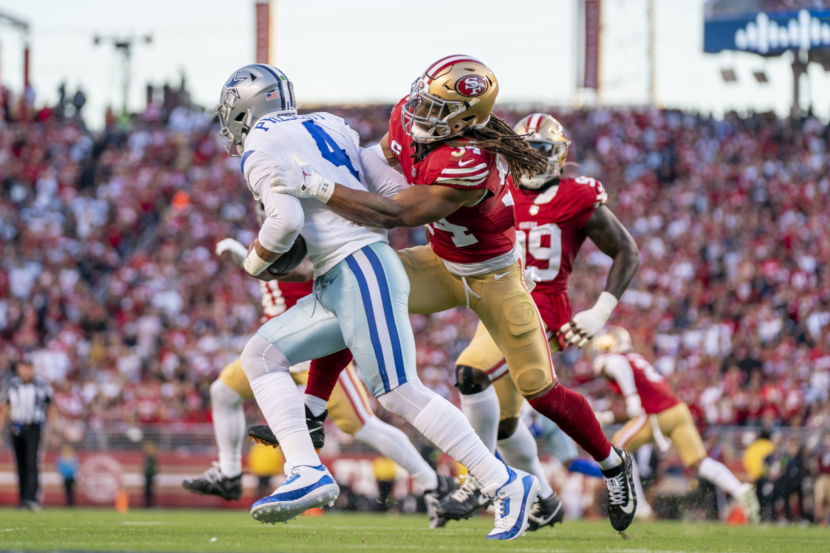 Dak Prescott tries to run with the ball as Fred Warner reaches out to sack him