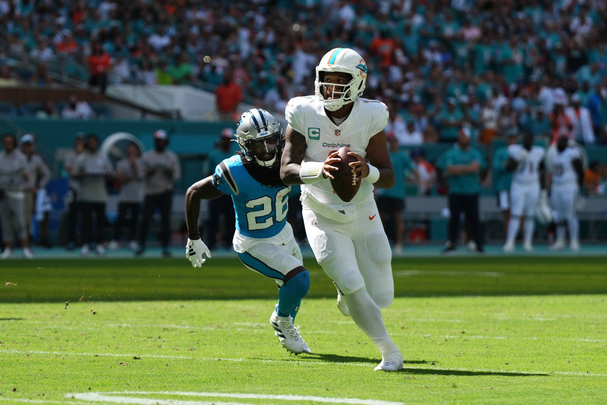 Tua Tagovailoa runs with the ball as a Panthers defender runs after him