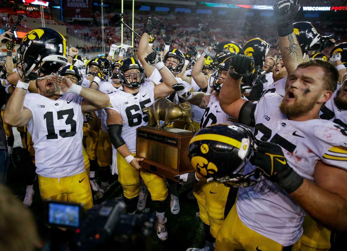 Iowa defensive end Joe Evans (13), offensive lineman Logan Jones (65), offensive lineman Joe Huber (60) and defensive lineman Logan Lee (85) celebrate with the Heartland Trophy after defeating Wisconsin on Saturday, October 14, 2023, at Camp Randall Stadium in Madison, Wis. Iowa won the game, 12-6.