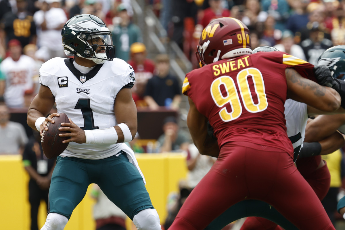 Philadelphia Eagles quarterback Jalen Hurts (1) prepares to pass the ball as Washington Commanders defensive end Montez Sweat (90) chases during the first quarter at FedExField.