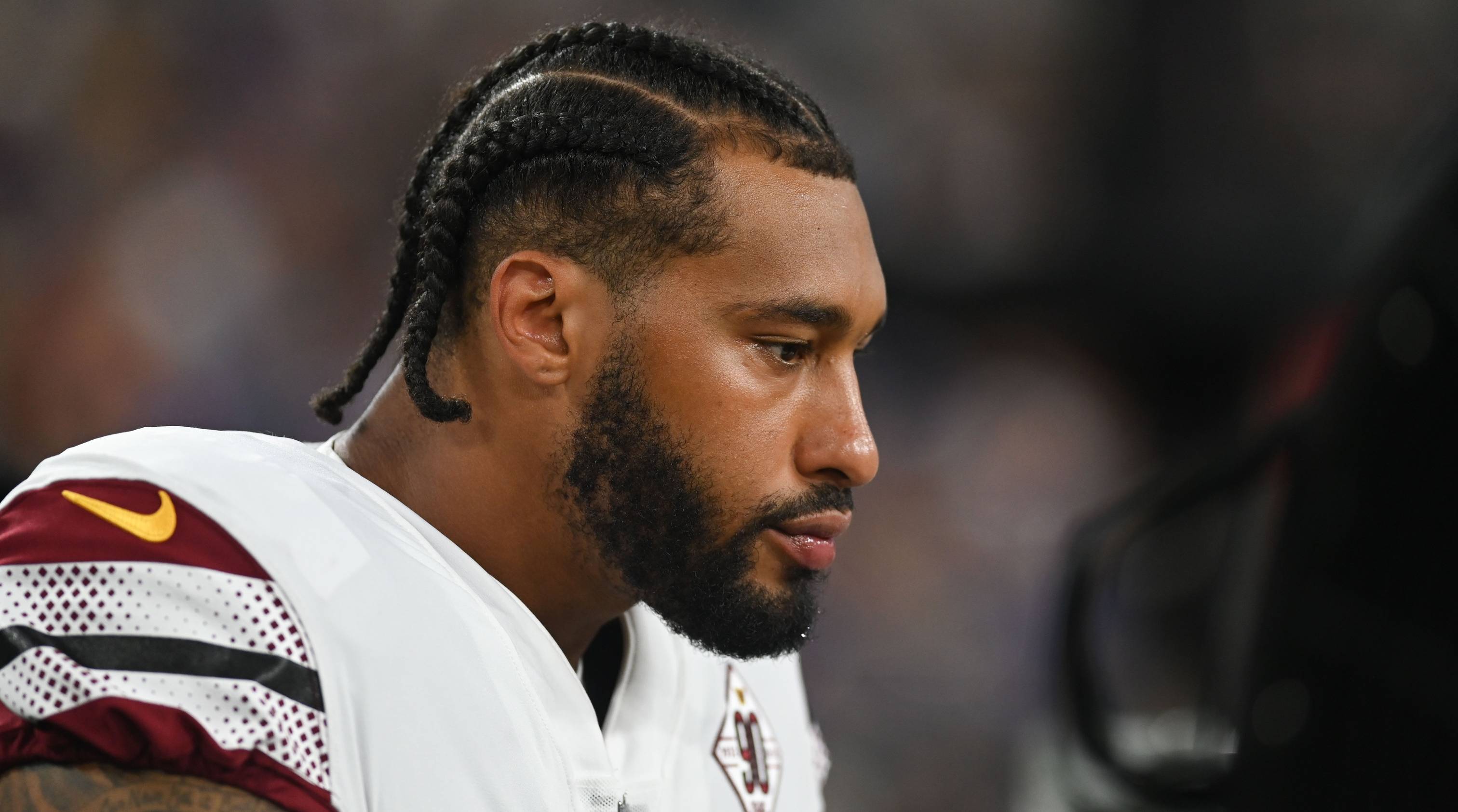 Commanders pass rusher Montez Sweat looks on without a helmet during a game.