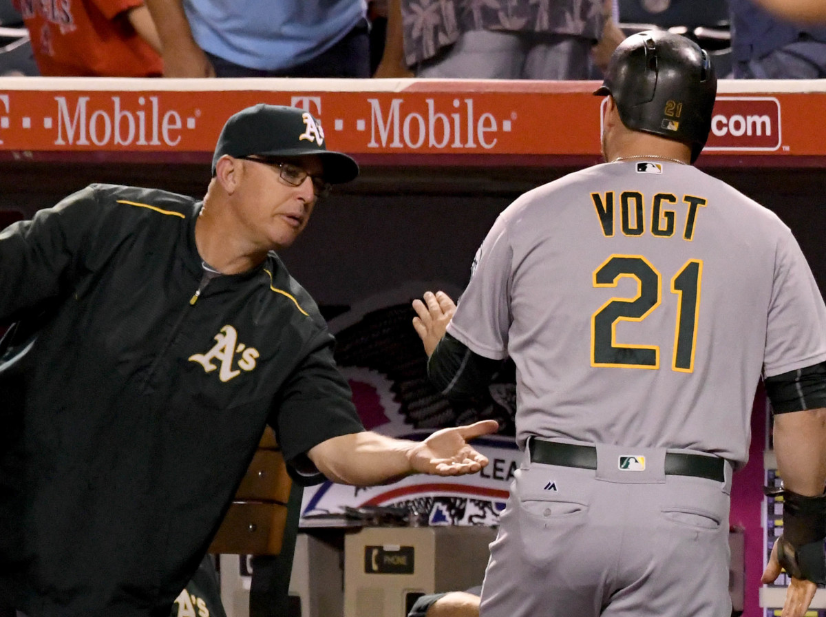 Sep 28, 2016; Anaheim, CA, USA; Oakland Athletics catcher Stephen Vogt (21) is greeted at the dugout by Oakland Athletics manager Bob Melvin (6) after scoring a run in the first inning of the game against the Los Angeles Angels at Angel Stadium of Anaheim.