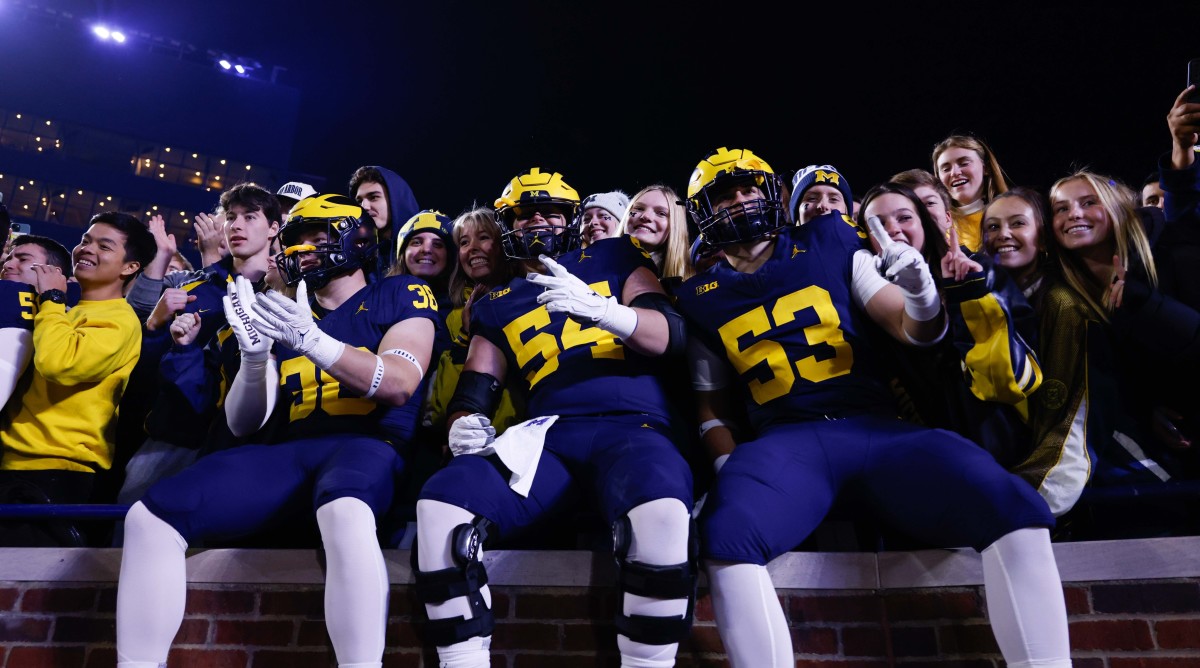 Michigan football players celebrate in the stands with fans after a win over Purdue.