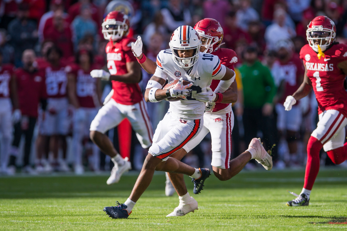 Nov 11, 2023; Fayetteville, Arkansas, USA; Auburn Tigers wide receiver Caleb Burton III (10) runs after a catch as Arkansas Razorbacks defensive lineman Nico Davillier (0) tries to bring him down during the first quarter at Donald W. Reynolds Razorback Stadium. Mandatory Credit: Brett Rojo-USA TODAY Sports  