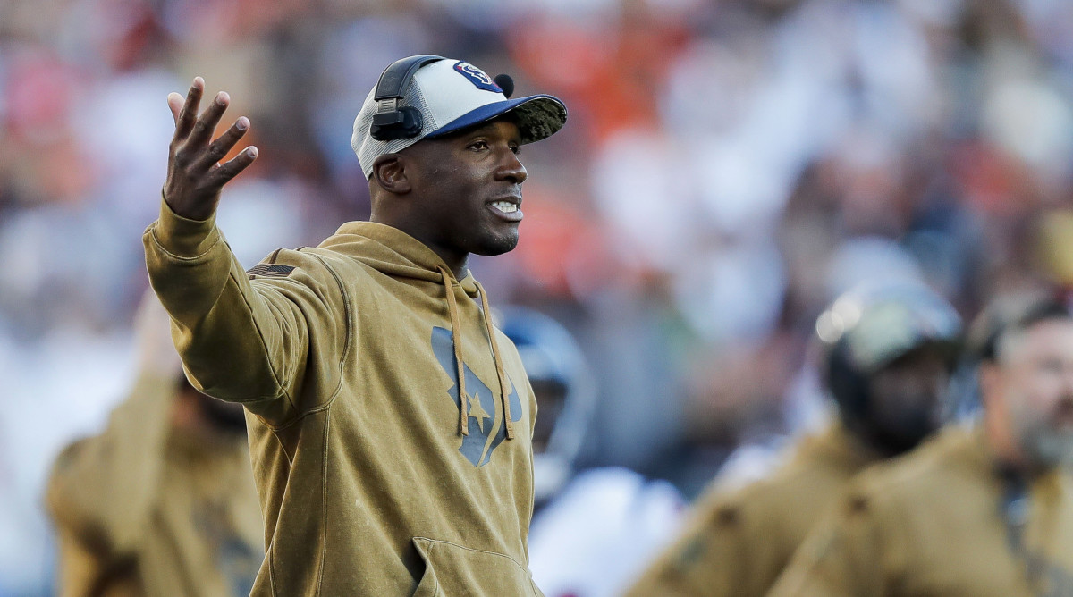 DeMeco Ryans puts his right hand out as he wears a headset on the sideline