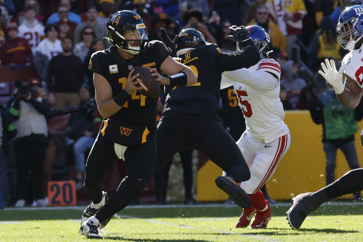 Washington Commanders quarterback Sam Howell (14) scrambles from New York Giants linebacker Kayvon Thibodeaux (5) during the first quarter at FedExField.