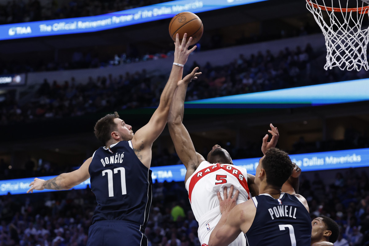 Dallas' Luka Doncic and Toronto's Precious Achiuwa reach for a rebound.