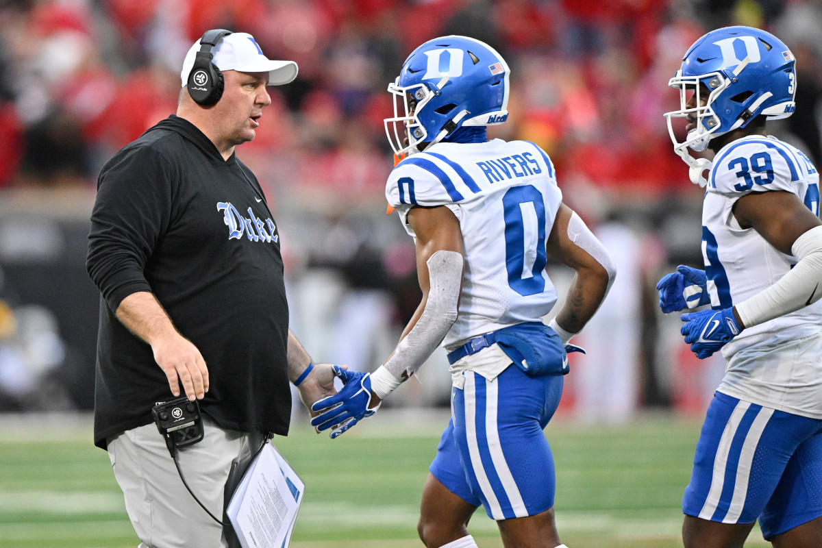 Former Duke coach Mike Elko shaking hands with players as they walk off the field at Wallace Wade Stadium.