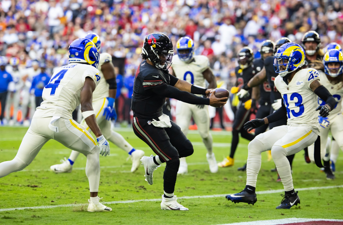 Kyler Murray runs with the ball extended in his hands in front of him as Rams defenders surround him