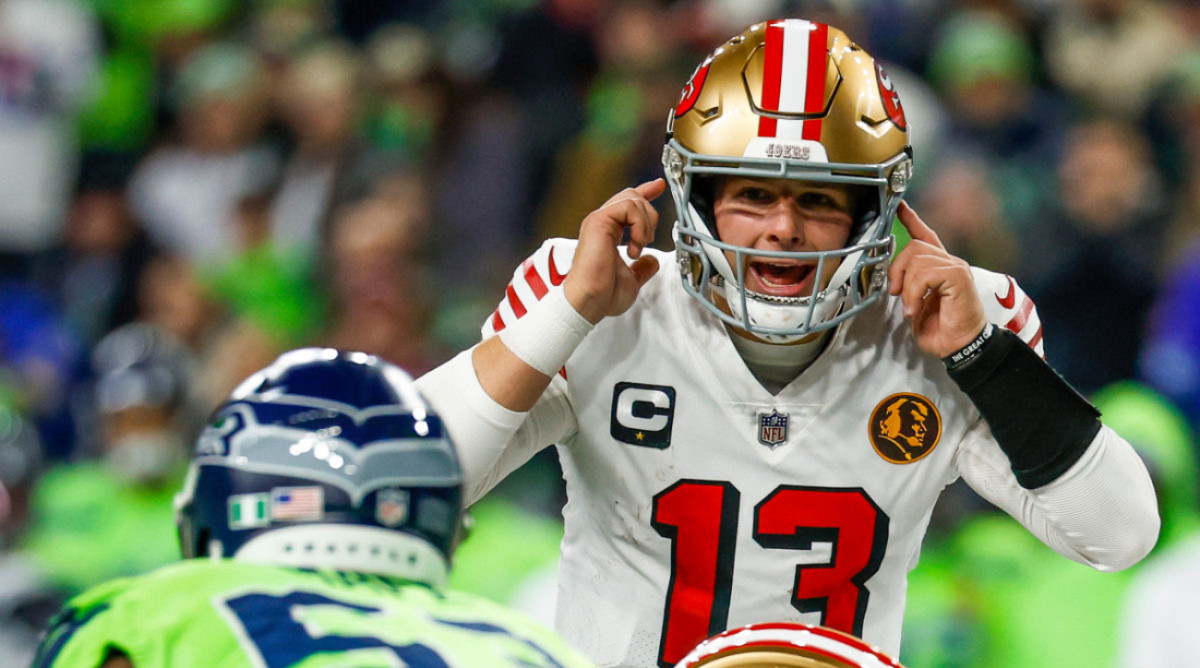 San Francisco 49ers quarterback Brock Purdy makes a gesture to is helmet during a game with the Seattle Seahawks.