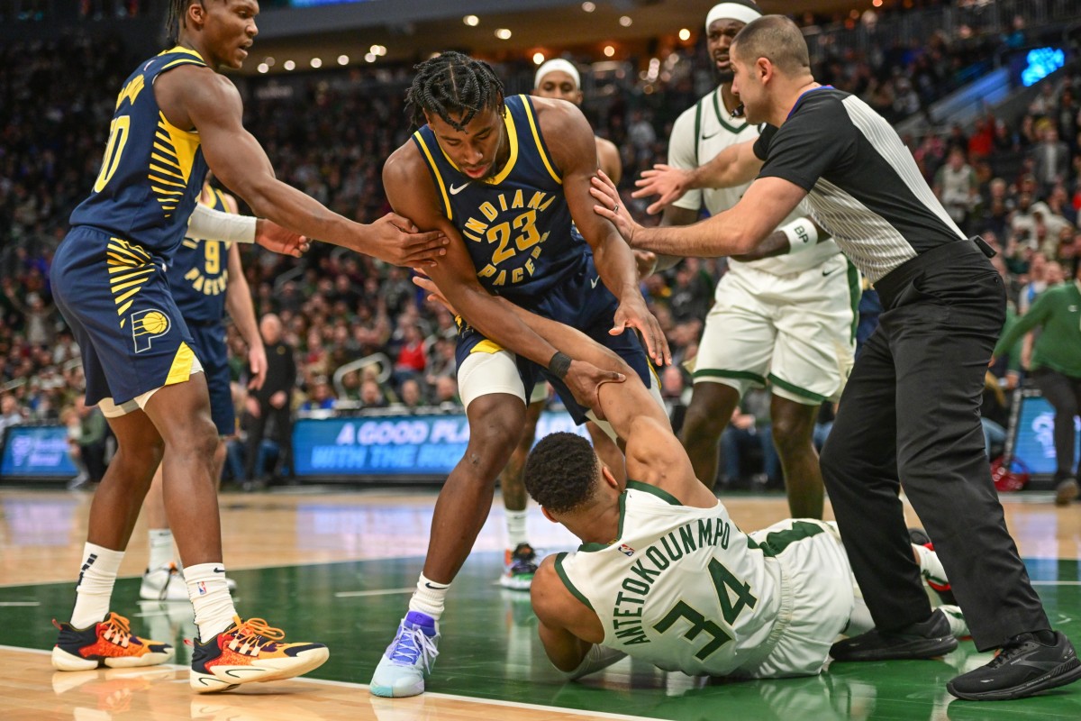 Indiana Pacers center Aaron Nesmith (23) helps Milwaukee Bucks forward Giannis Antetokounmpo (34) after a foul i