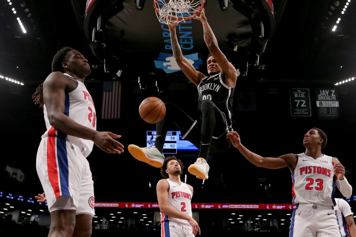 Brooklyn Nets center Nic Claxton (33) hangs on the rim after dunking against Detroit Pistons center Isaiah Stewart (28) and guards Cade Cunningham (2) and Jaden Ivey (23) 