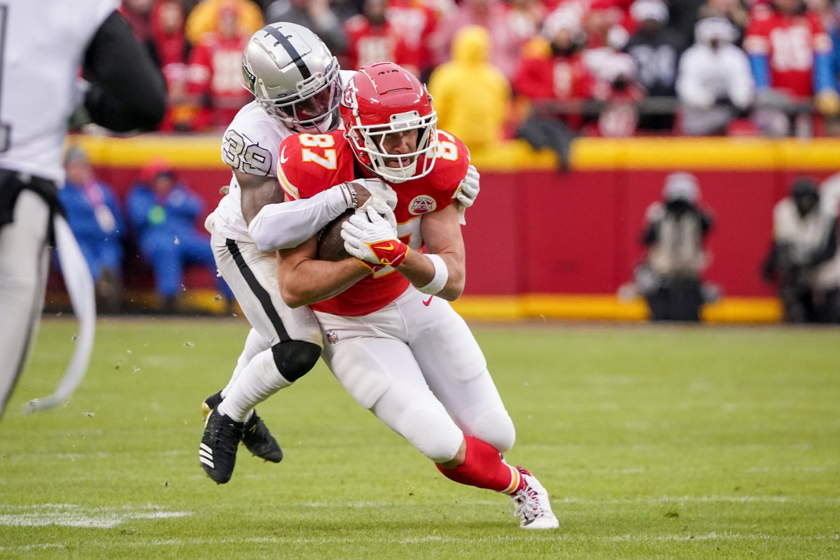 Travis Kelce runs with the ball as Nate Hobbs tackles him from behind