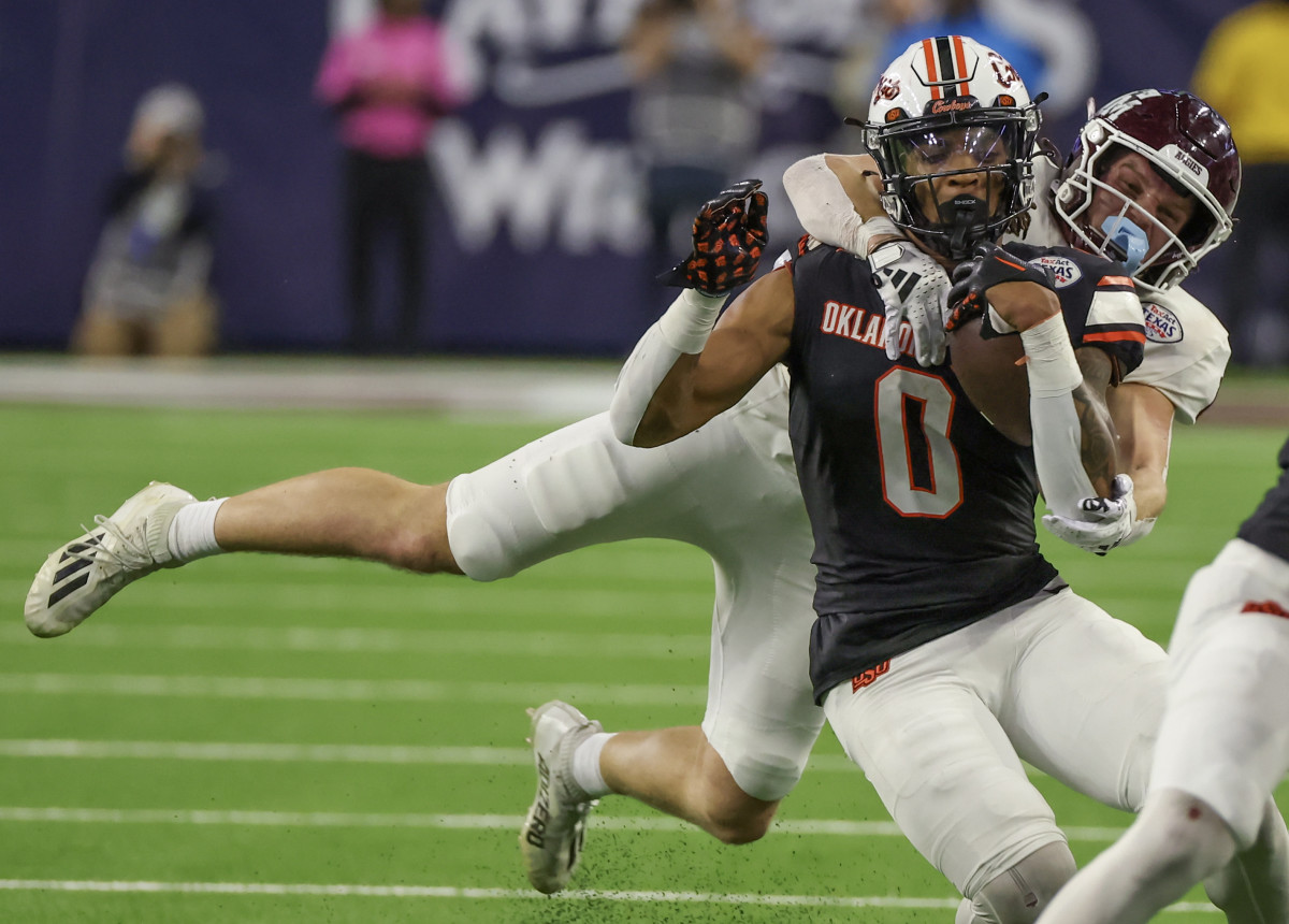 Dec 27, 2023; Houston, TX, USA; Oklahoma State Cowboys running back Ollie Gordon II (0) is tackled by Texas A&M Aggies linebacker Sam Mathews (12) in the second half at NRG Stadium. Mandatory Credit: Thomas Shea-USA TODAY Sports 