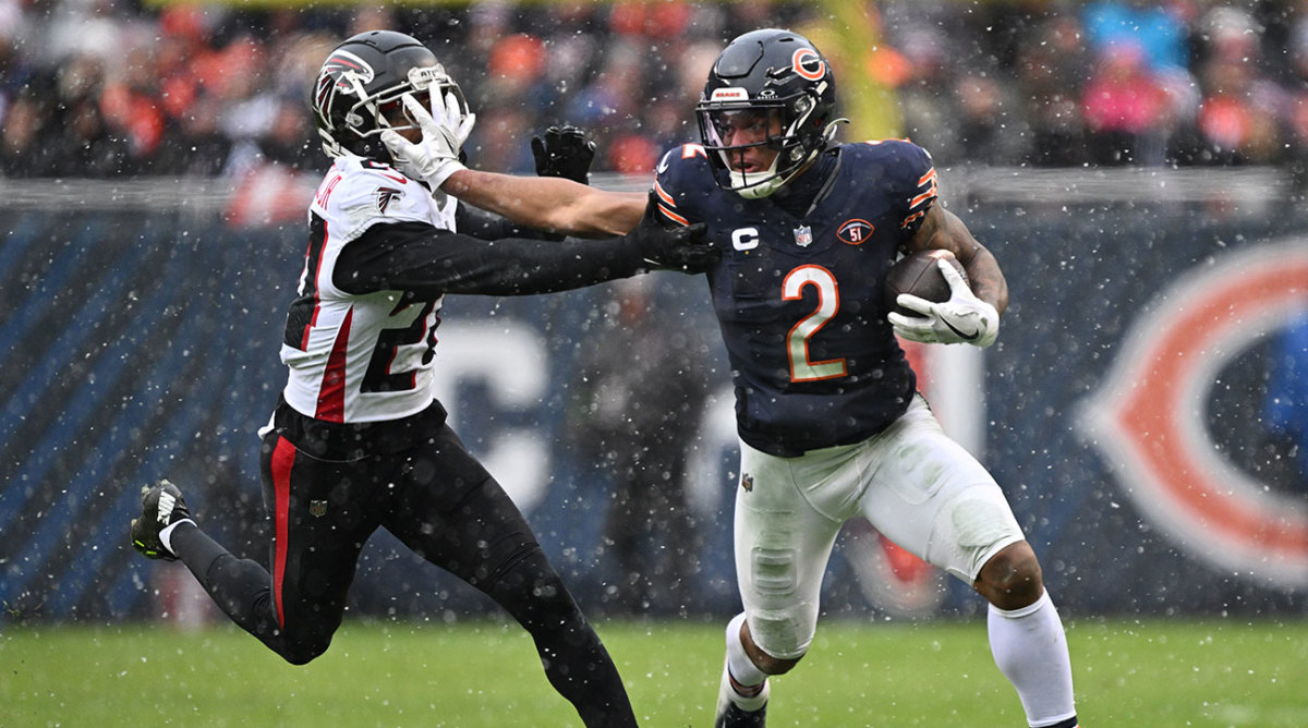 DJ Moore stiff-arms a Falcons defender as he runs with the ball.