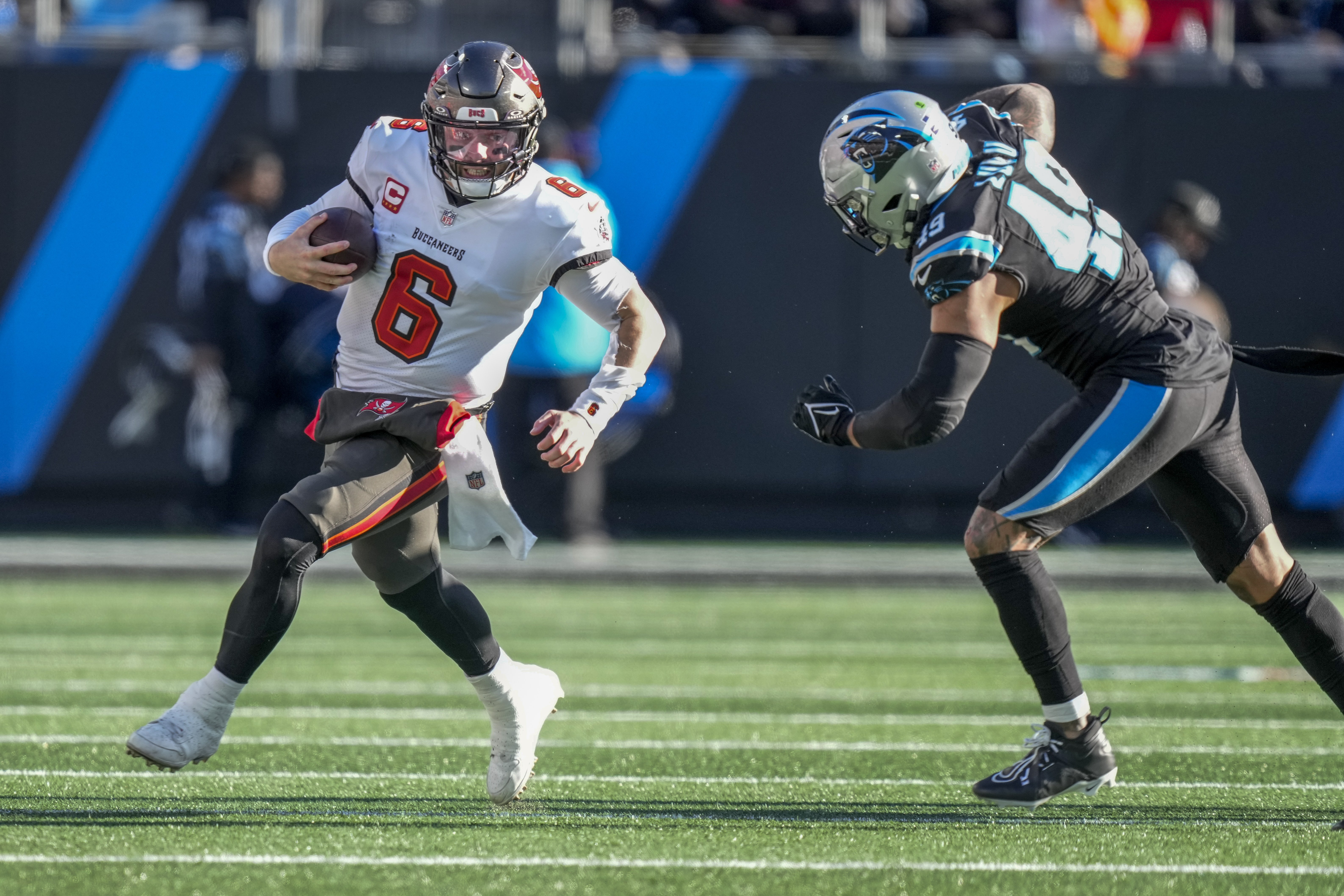 Baker Mayfield runs with the ball as a Panthers player lunges to tackle him