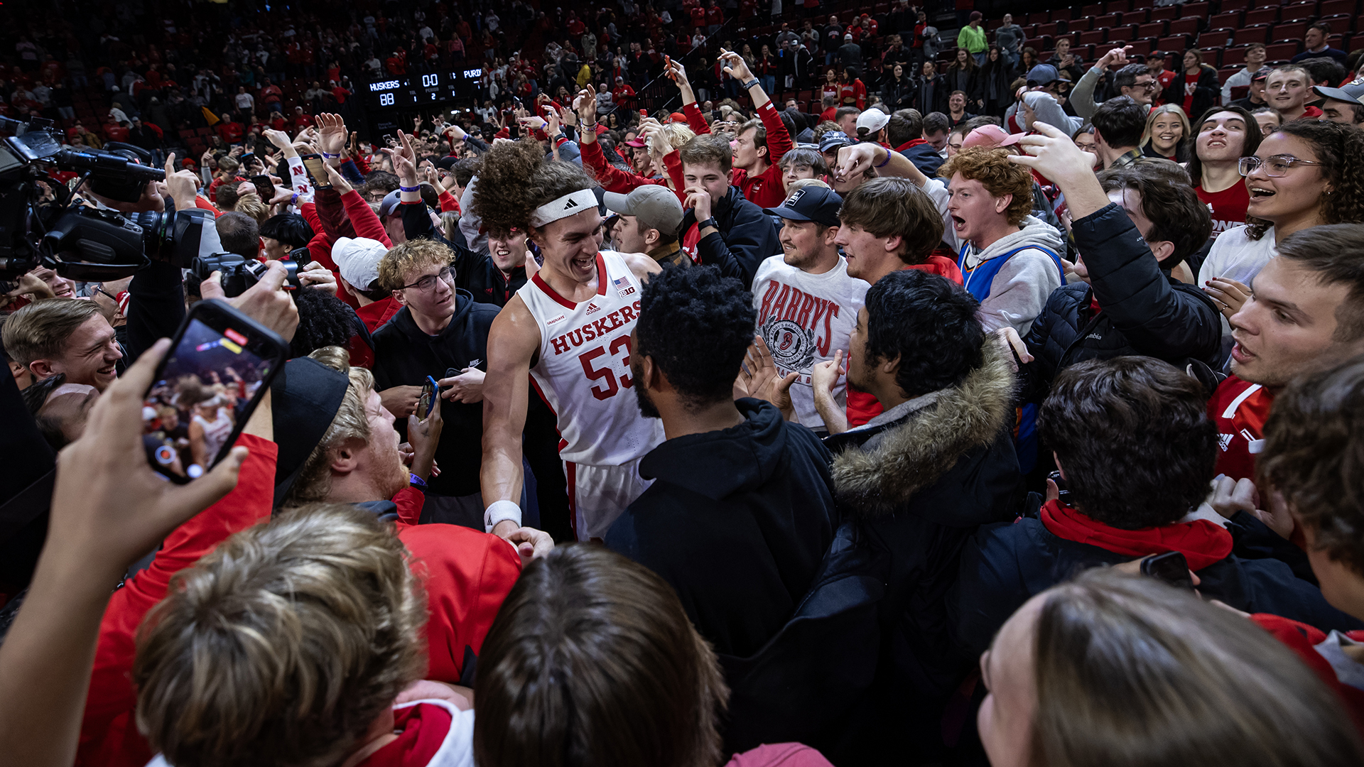 Fans and players celebrate on the court at Pinnacle Bank Arena.