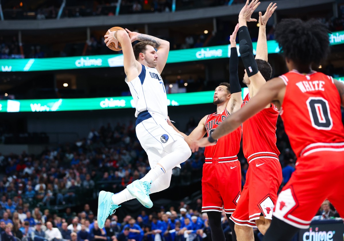 Dallas Mavericks guard Luka Doncic (77) passes over Chicago Bulls guard Zach LaVine (8) and Chicago Bulls center Nikola Vucevic (9) and Chicago Bulls guard Coby White (0) during the first quarter at American Airlines Center.