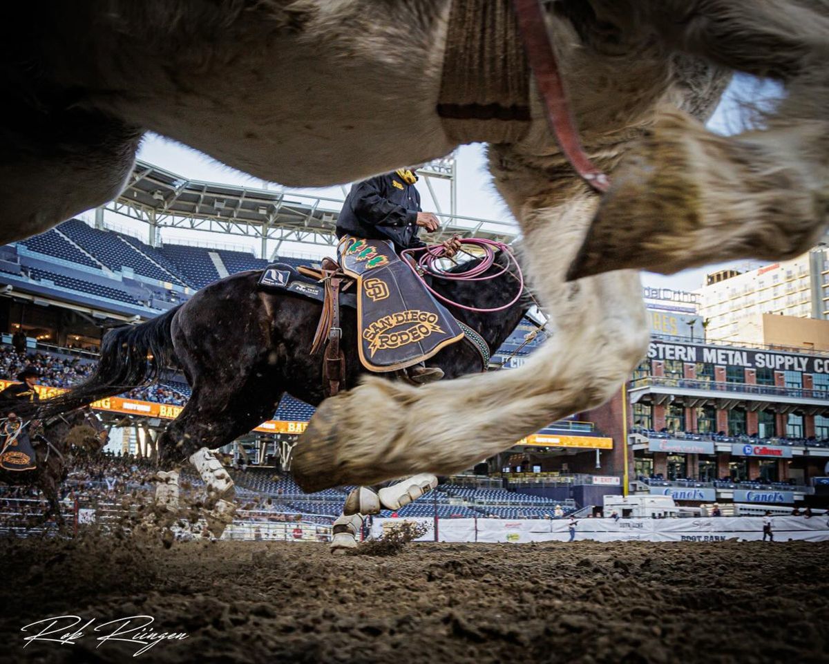 View from the dirt of the pickup men and a bucking horse at the Padres Stadium in San Diego, CA.