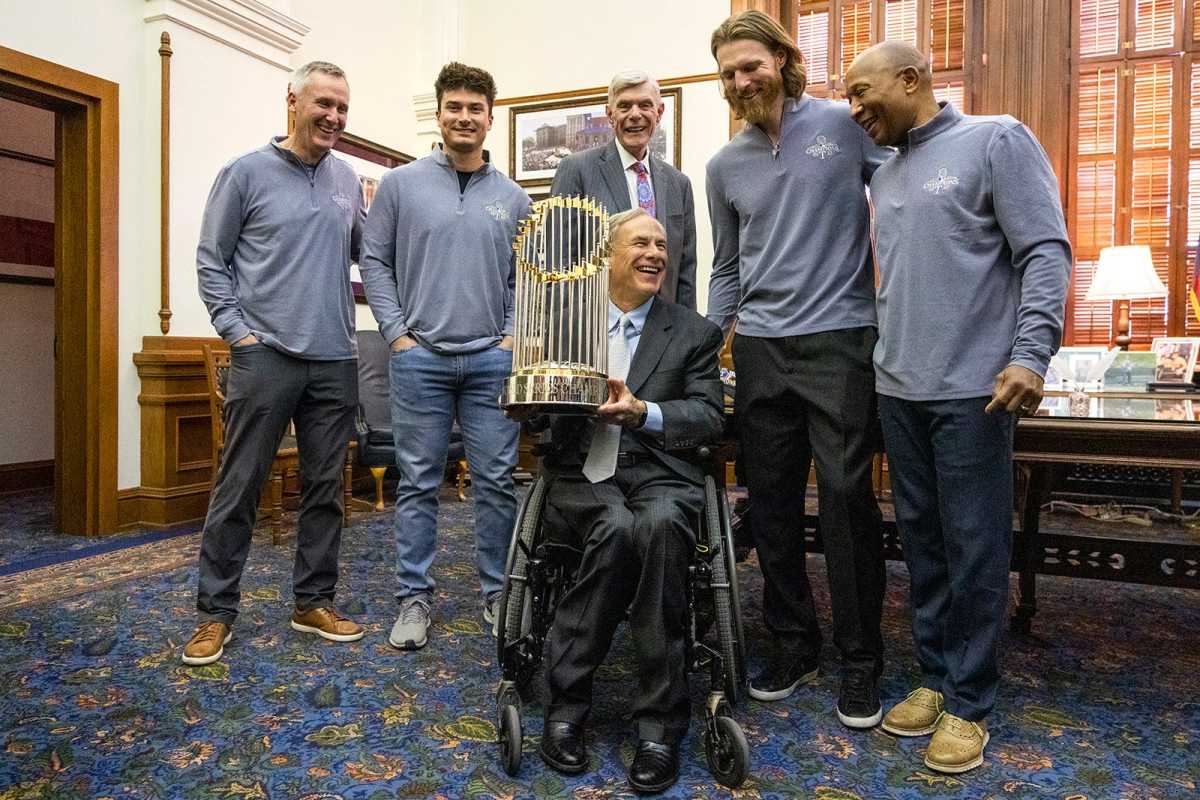 Governor Greg Abbott poses with the World Series championship trophy on Thursday at the Capitol in Austin after presenting a congratulatory proclamation to members of the Texas Rangers following the team's first World Series. Abbott is flanked, from left, by Rangers television announcer Dave Raymond, minor league infielder Justin Foscue, Rangers owner Ray Davis, pitcher Jon Gray, and third base coach Tony Beasley.