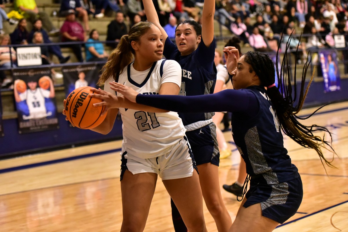 El Reno senior Pauline Black-Harmon (21) seeks to elude a double team by Shawnee during a game on Feb. 13, 2024.